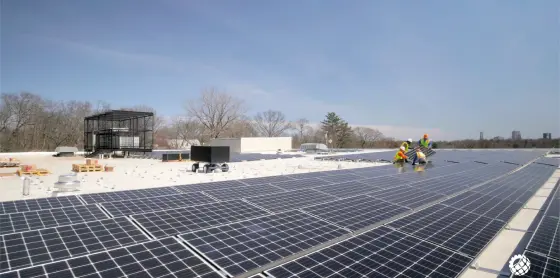 Technicians-installing-a-solar-energy-system-on-a-commercial-rooftop-surrounded-by-snow-and-HVAC-units