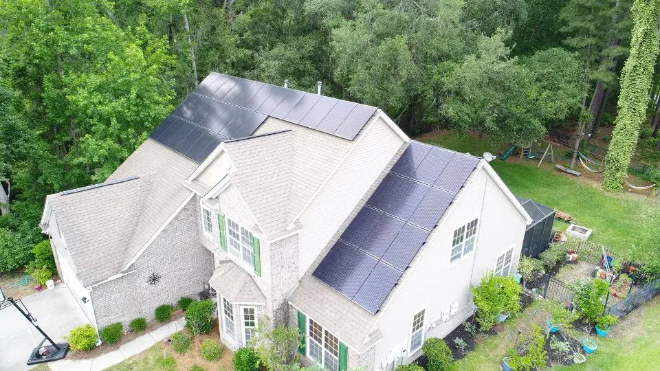 house-with-rooftop-solar-panels-surrounded-by-trees-and-backyard-garden